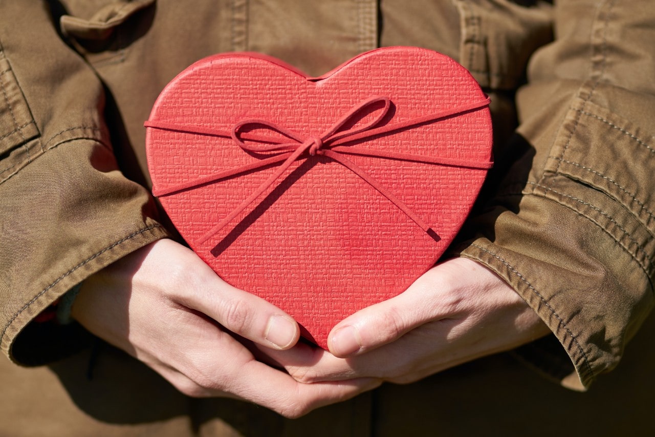 A man holding a red heart-shaped box to give to their Valentine