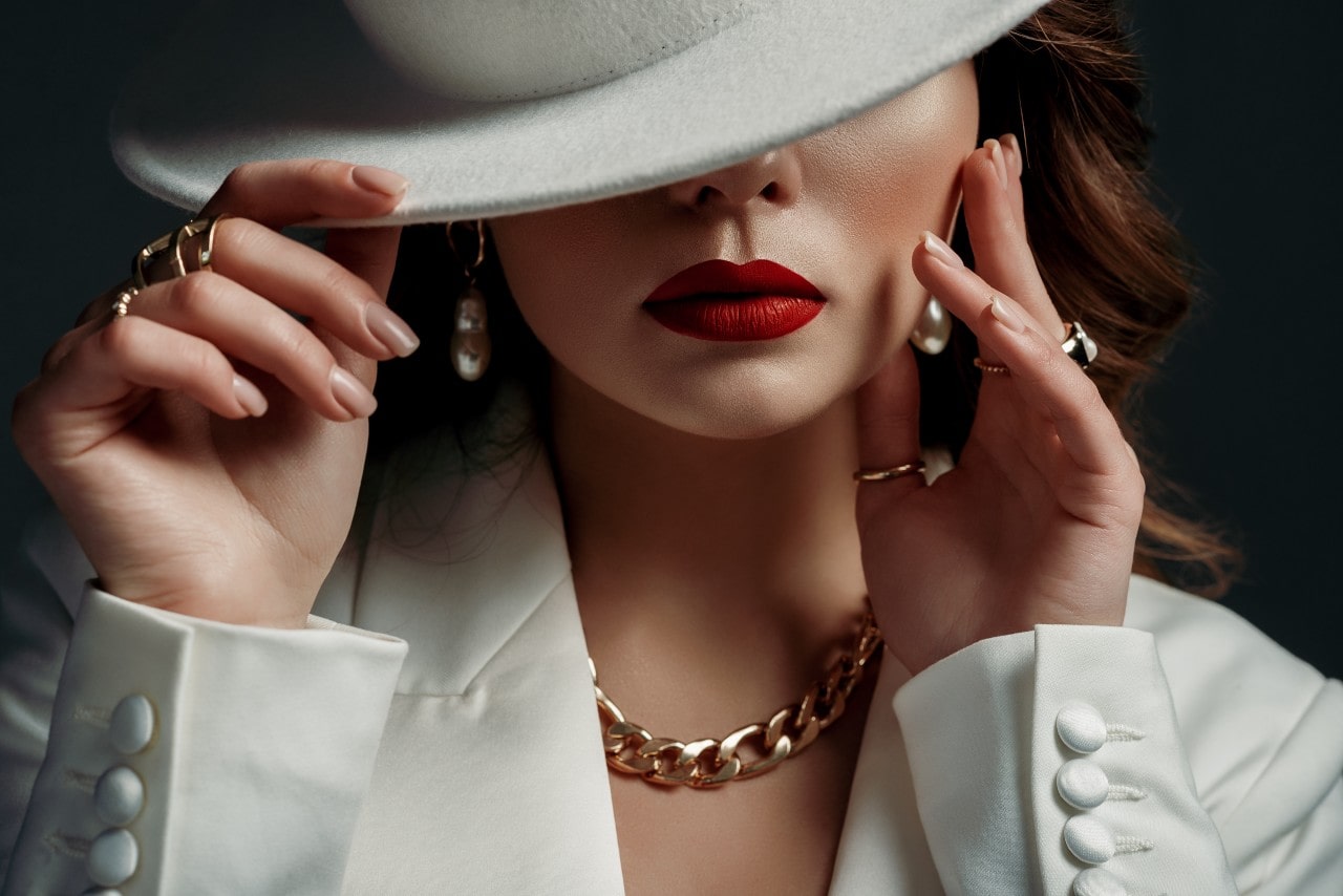 Sophisticated woman wearing pearl drop earrings and gold chain necklace along with fashion rings