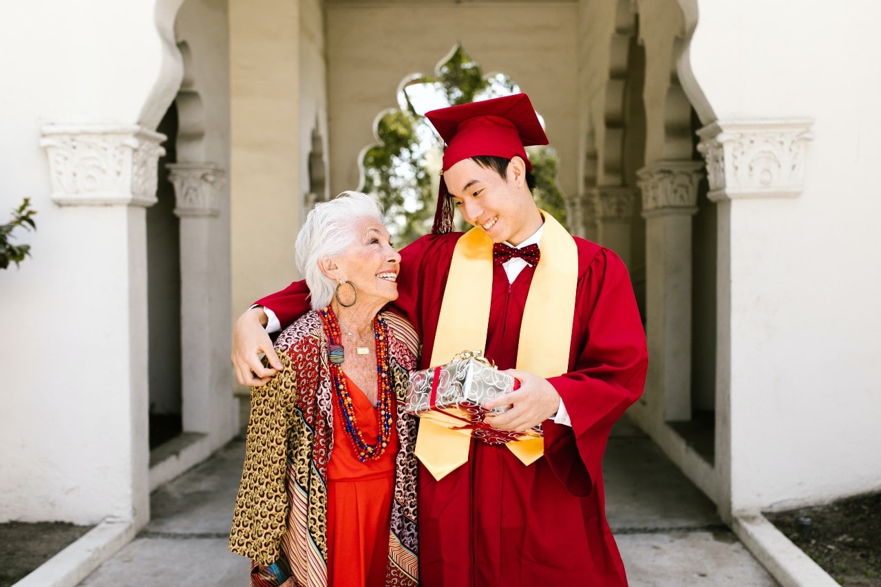 Proud college graduate receiving a gift from his wife