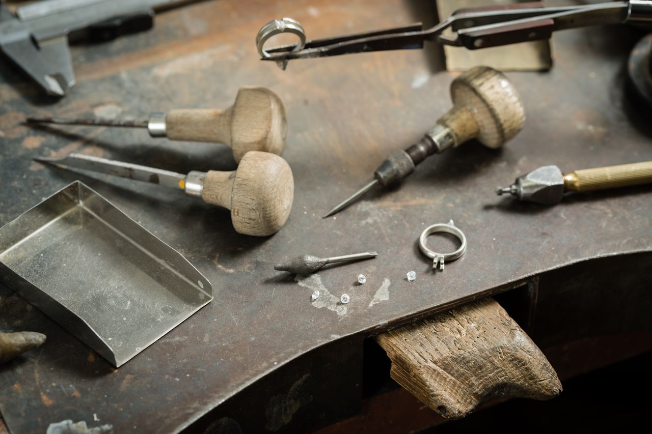 Different jewelry tools on a work top with a ring setting and different diamonds.